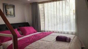 A bedroom with a bed, a window with curtains, a framed picture on the wall, and a wooden ladder. - OYO 94320 Homestay Abah Hank Syariah (Yogyakarta)