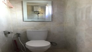 A small bathroom with a toilet, a showerhead, and a mirror. - OYO 94320 Homestay Abah Hank Syariah (Yogyakarta)