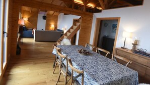 Ein Holzinterieur mit Esstisch, Stühlen, einer Couch und einer Treppe.
