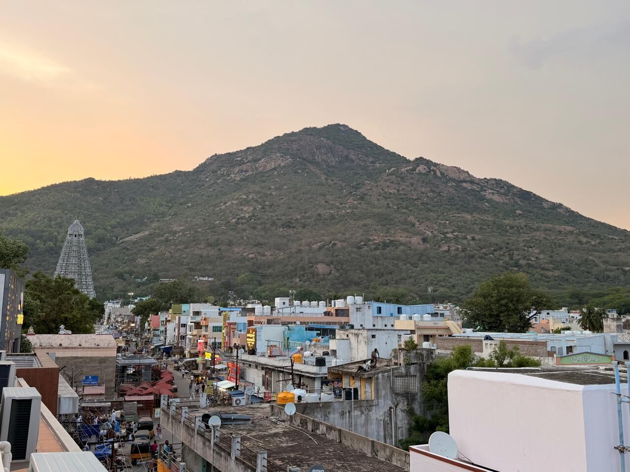 A town with a prominent hill in the background, buildings with flat roofs, and a temple-like structure.