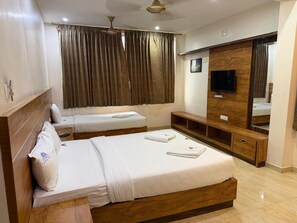Habitación de hotel con dos camas, televisor, muebles de madera y un espejo.