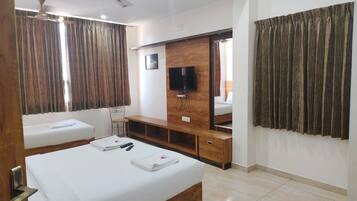A hotel room with a bed, a desk, a chair, a television, and a large mirror.