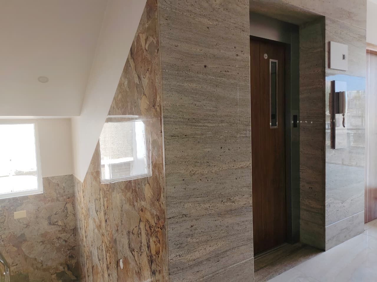A modern interior with a stone wall, a wooden door, and a small window.