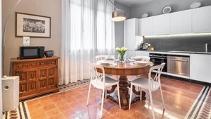 A modern kitchen with white cabinets, a dining table set for four, and a large window with curtains. - Ca' delle Contesse   Luxury waterfront apartment (Lido)