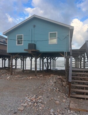 A two-story house with a balcony, wooden deck, and a view of the ocean.