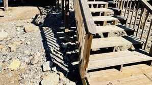 A wooden pier leading to a house with a blue exterior.