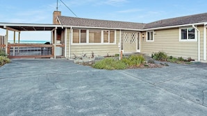 A two-story house with a covered porch, a garage, and a small garden area. - Dungeness Waterfront, Hot tub, Fire Pit, Pets OK (Sequim)