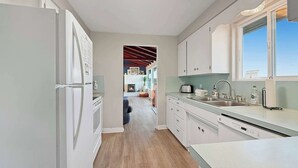 A narrow kitchen with white cabinets, a built-in oven, and a window above the sink. - Dungeness Waterfront, Hot tub, Fire Pit, Pets OK (Sequim)