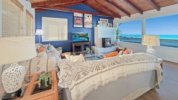 A cozy living room with a fireplace, a television, and a view of the beach. - Dungeness Waterfront, Hot tub, Fire Pit, Pets OK (Sequim)