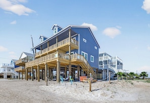 A beachfront property with multiple levels, wooden deck, and a beach view.
