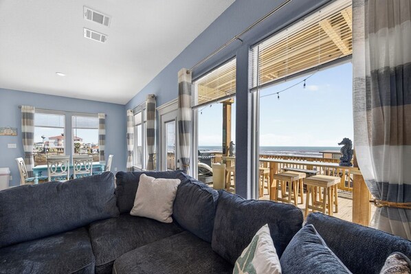 A modern living room with a large window overlooking a deck and the sea.