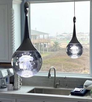 A kitchen with a window, a sink, and two pendant lights.