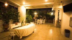 A covered outdoor dining area with tables and chairs, surrounded by potted plants and trees. - Townhouse OAK Metro Manila Near Osmena Highway PNR Pasay formerly Avitel Hotel (Makati)