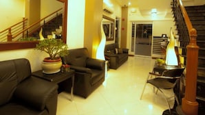 A spacious living area with a staircase, a sofa, a coffee table, and a potted plant. - Townhouse OAK Metro Manila Near Osmena Highway PNR Pasay formerly Avitel Hotel (Makati)