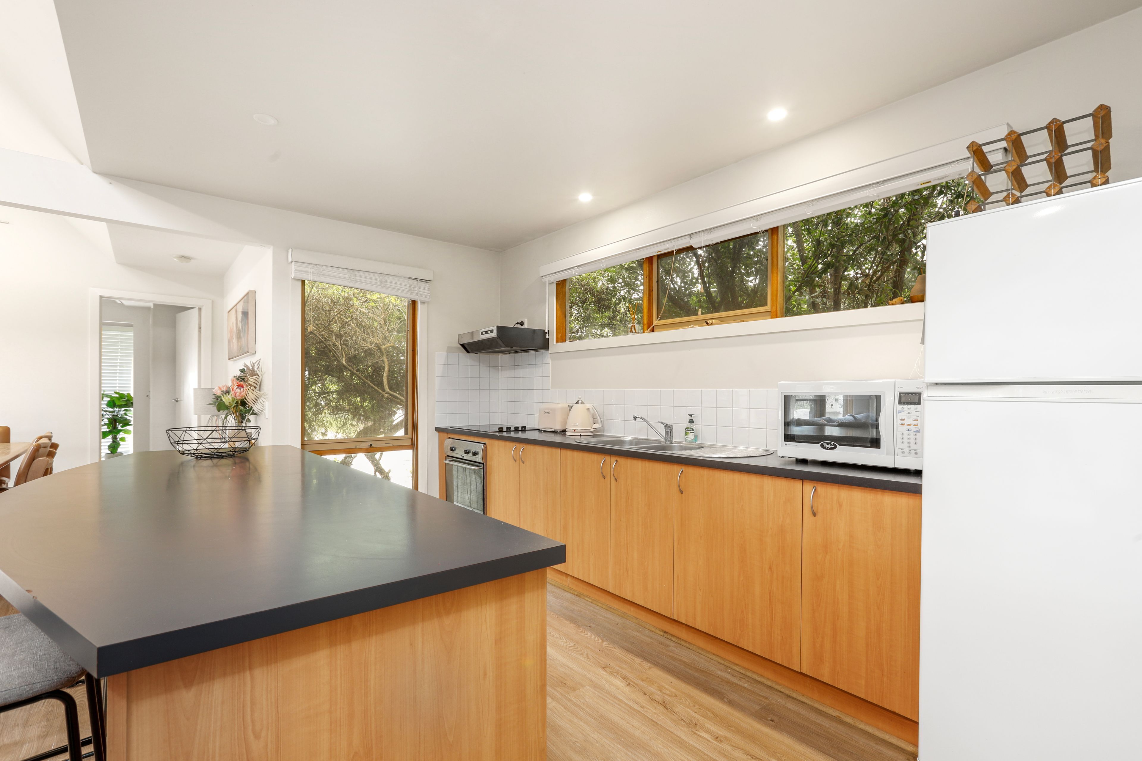 A modern kitchen with wooden cabinets, a black countertop, and a built-in oven.