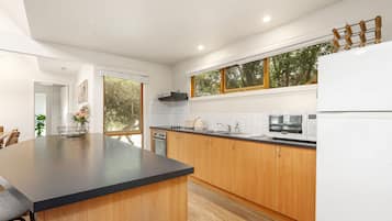 A modern kitchen with wooden cabinets, a black countertop, and a built-in oven.