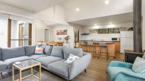 Una sala moderna con un sofá seccional gris, una mesita de centro de madera y un sofá verde azulado con cojines a rayas.