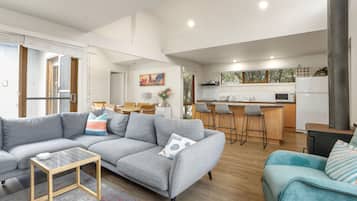 A modern living room with a grey sectional sofa, a small wooden coffee table, and a teal sofa with striped cushions.