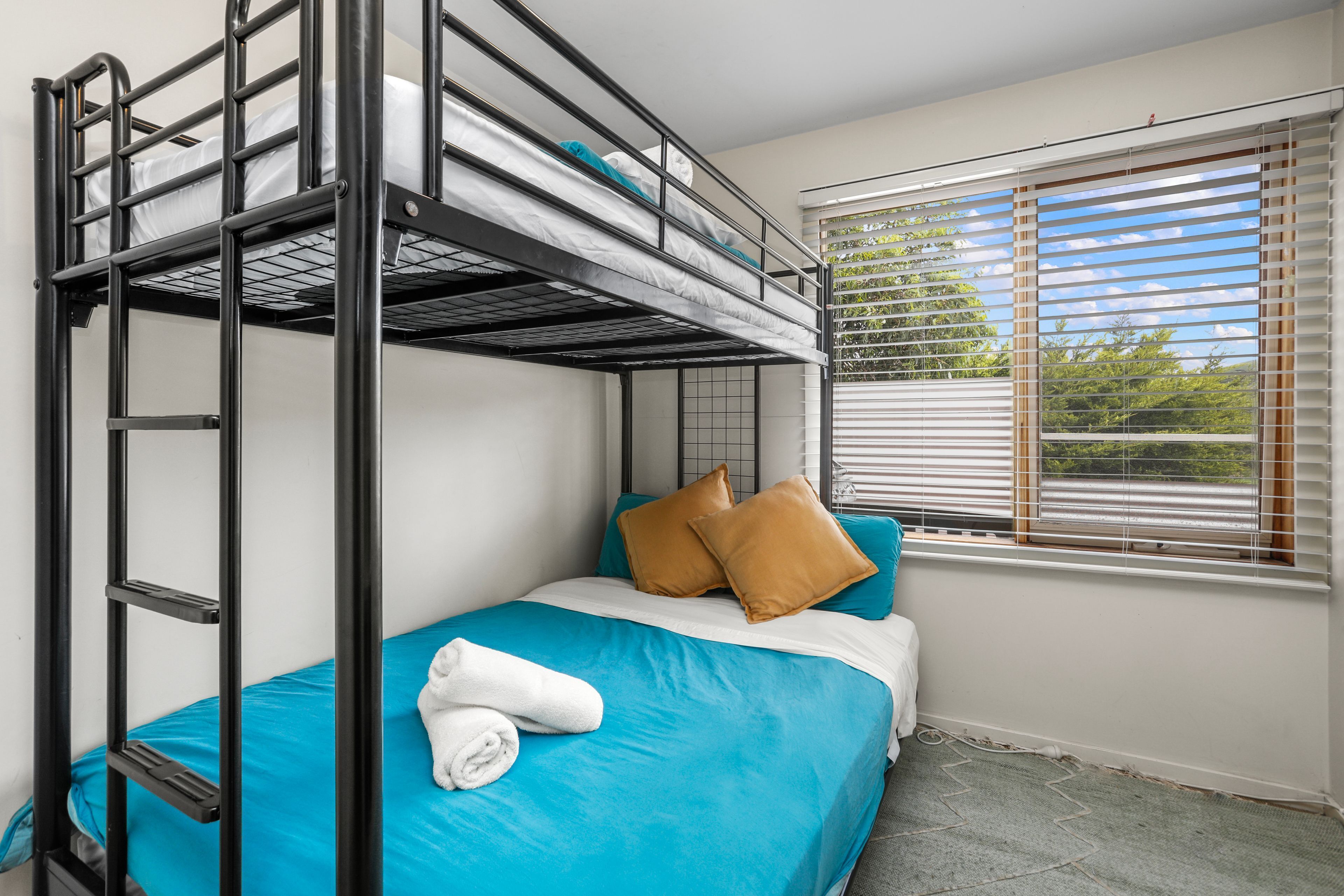 A bunk bed room with a window, a towel, and pillows.