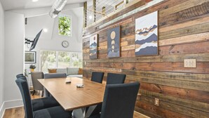 A conference room with a wooden table and black chairs, a clock on the wall, and artwork on the wooden panel wall. - Hot Tub|Sauna|Walkable|Reynoldstown Spa Retreat (Atlanta)
