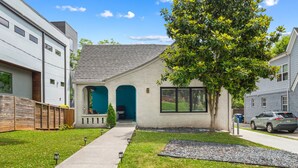 A modern two-story house with a front porch, a tree, and a driveway. - Hot Tub|Sauna|Walkable|Reynoldstown Spa Retreat (Atlanta)