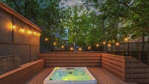 A hot tub on a wooden deck with string lights, surrounded by trees and a wooden fence. - Hot Tub|Sauna|Walkable|Reynoldstown Spa Retreat (Atlanta)