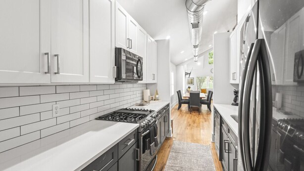 A modern kitchen with white cabinets, a stainless steel refrigerator, and a microwave. - Hot Tub|Sauna|Walkable|Reynoldstown Spa Retreat (Atlanta)