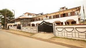 A large, multi-story building with a prominent black gate, a balcony, and a street view. - Lazo Silver Lake (Ootacamund)
