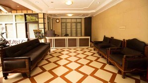 A reception area with a check-in counter, a clock, and a patterned floor. - Lazo Silver Lake (Ootacamund)