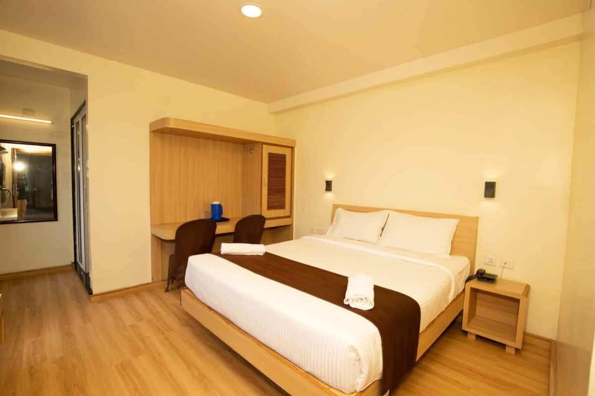 Ein Hotelzimmer mit einem großen Bett, einem Schreibtisch, einem Stuhl und einem Kleiderschrank.