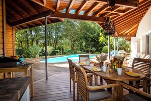 A wooden deck with a pool, surrounded by lush greenery. - Exceptional residence on the Biscarrosse golf course with a heated pool (Biscarrosse)