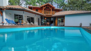 Une maison moderne dotée d’une piscine, d’une terrasse en bois et d’un espace salon extérieur.