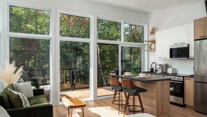 A modern kitchen with large windows, a dining area, and a cozy seating space.