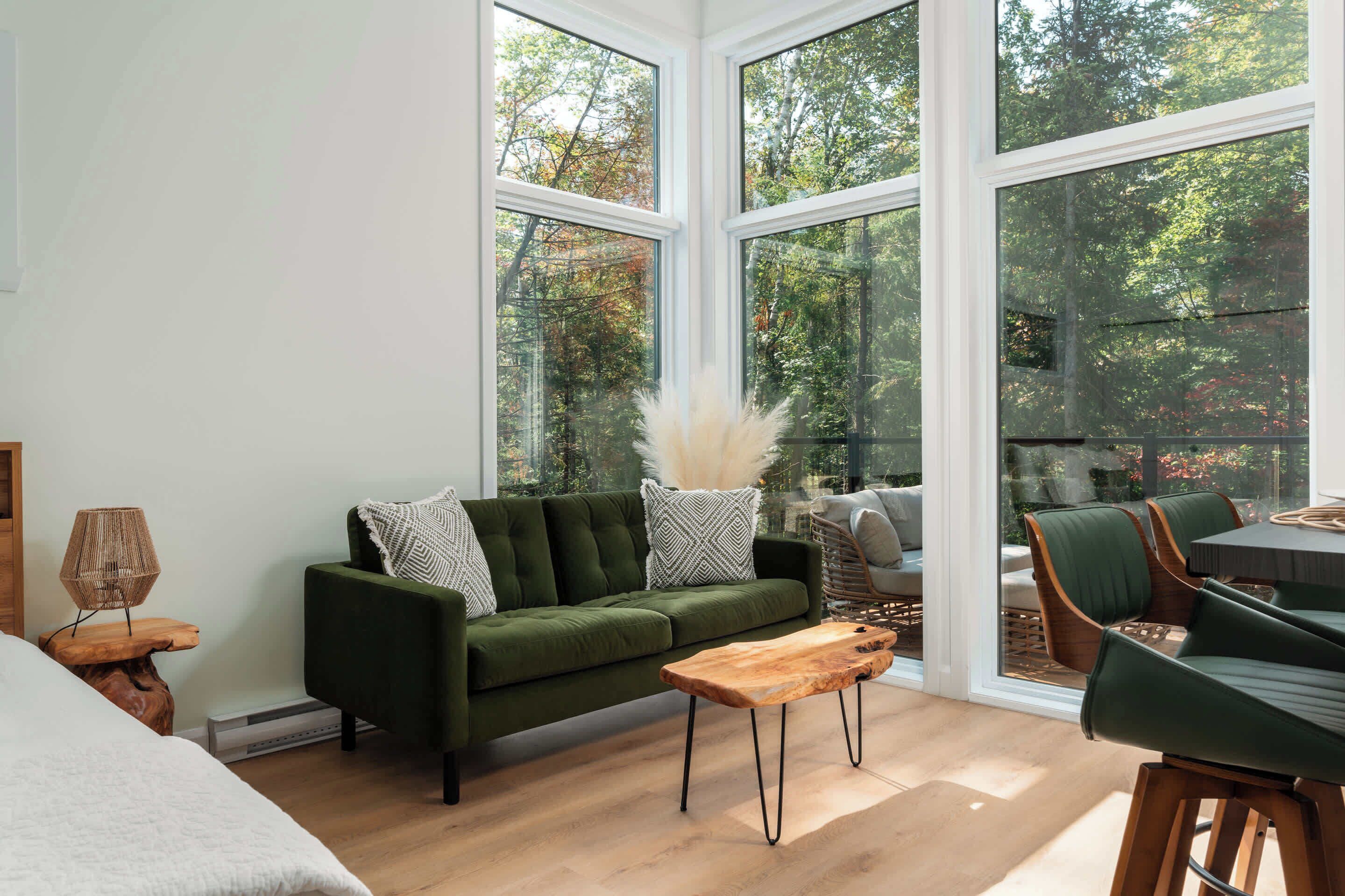 Un salon moderne avec un canapé vert, une table basse en bois et un coin repas avec des chaises vertes.