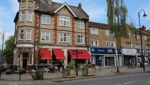A corner building with multiple shops including a pharmacy and a beauty salon. - Wanstead Gem  – Bright, Cosy & Immaculate High Street Apartment in East London (London)