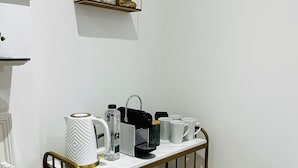 A small kitchenette with a marble countertop, a coffee maker, a kettle, and a water bottle. - Wanstead Gem – Bright, Cosy & Immaculate High Street Apartment in East London (London)