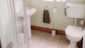 A bathroom with a toilet, sink, and a window with a plant. - Seamount Holiday Village No 26 (Courtown)
