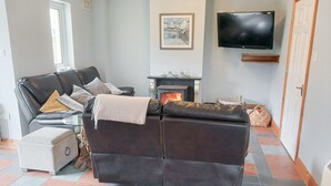 A living room with a leather sofa, a fireplace, a television, and a tiled floor. - Seamount Holiday Village No 26 (Courtown)