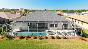 A modern house with a large glass-enclosed pool area and a covered patio. - Rotonda Palms - Amazing, Golf course, Pool, Spa, Convenient to everything! (Rotonda West)