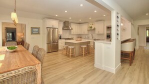 Una cocina moderna con armarios blancos, un refrigerador de acero inoxidable y una isla central con taburetes de bar.