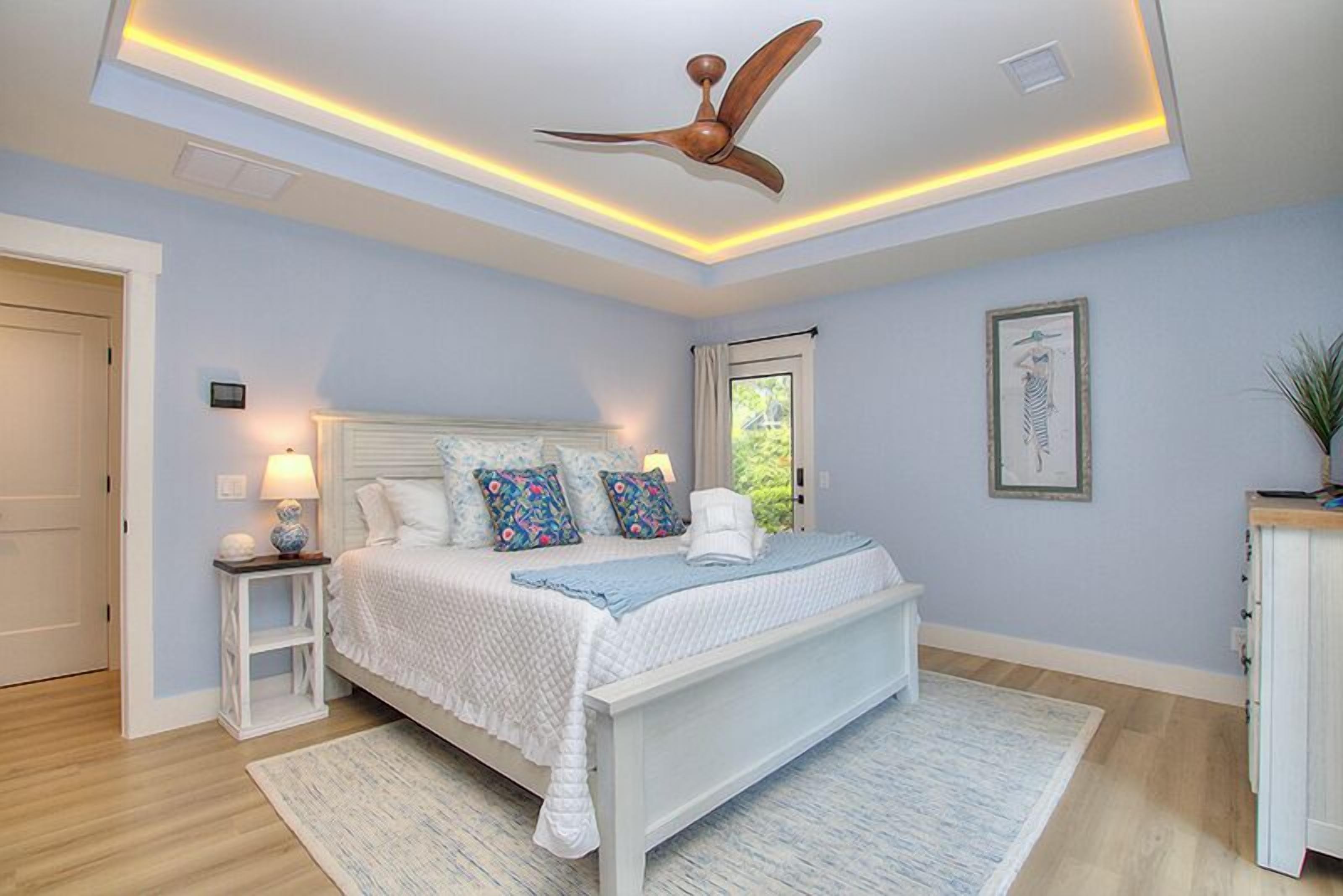A bedroom with a bed, nightstand, ceiling fan, and a window.
