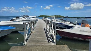 A wooden dock leading to a marina with several boats docked. - Bungalow Le Refuge Vert (Morne-à-l'Eau)