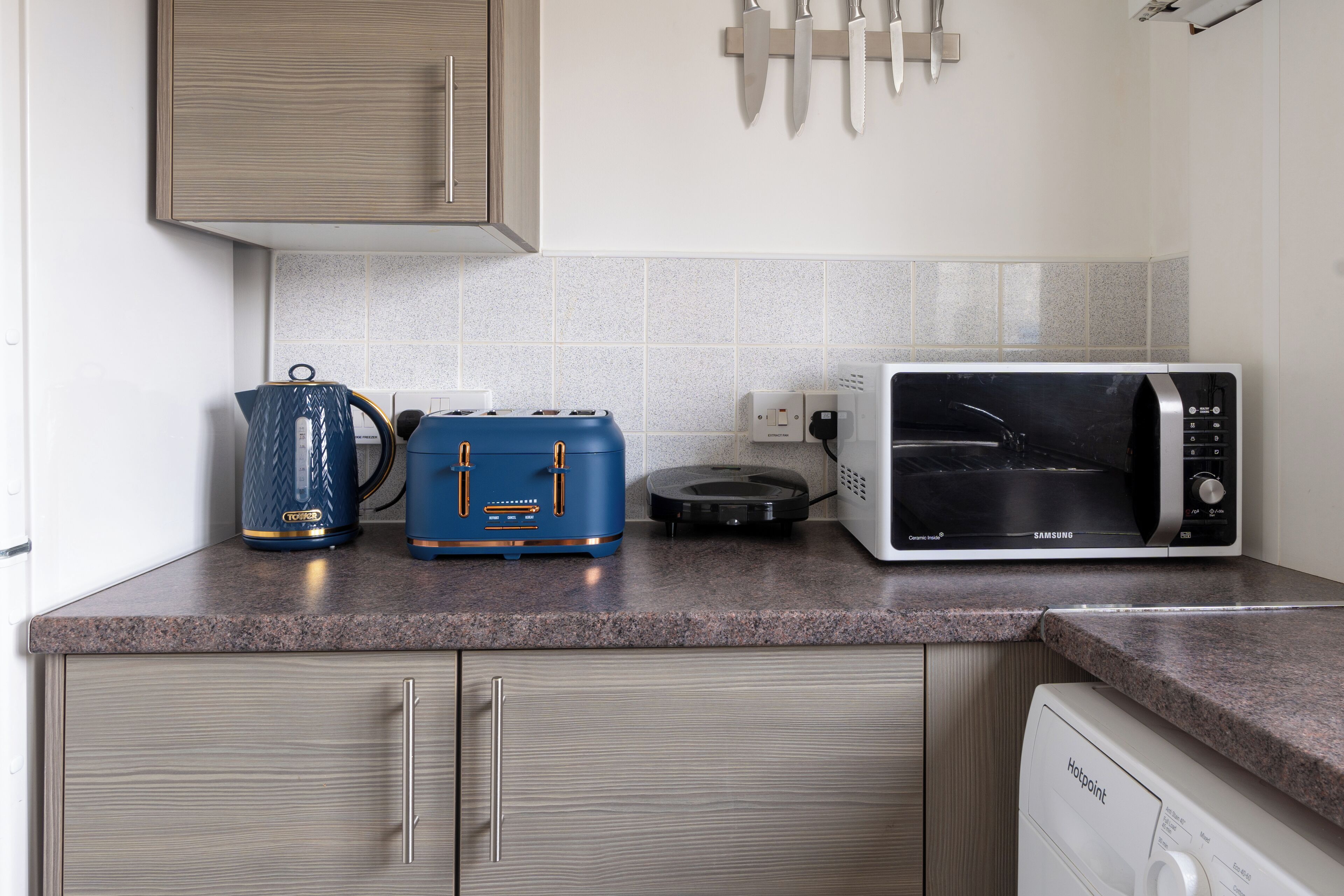 A kitchen with a microwave, toaster, and kettle on the countertop.
