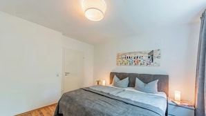 A bedroom with a bed, bedside table, and a wall-mounted artwork. - Cozy Stylish Berlin Apartment With 2 Bedrooms (Berlin)