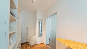 A hallway with a wooden floor, white walls, and a white closet with shelves. - Cozy Stylish Berlin Apartment With 2 Bedrooms (Berlin)
