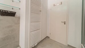 A hallway with a white door, a glass shelf with a basket, and a white radiator. - Cozy Stylish Berlin Apartment With 2 Bedrooms (Berlin)