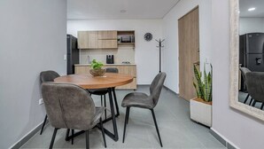 A modern kitchen with wooden cabinets, a microwave, and a clock on the wall. - Luxury Studio - Tesoro, Provenza, and Parque Lleras (Medellín)