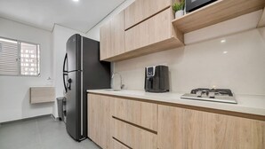 A modern kitchen with a stainless steel refrigerator, a coffee maker, and a gas stove. - Luxury Studio - Tesoro, Provenza, and Parque Lleras (Medellín)