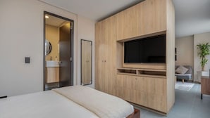 A modern bedroom with a bed, a TV mounted on a wooden cabinet, and a bathroom visible through an open door. - 7th floor modern apartment close to parque lleras (Medellín)