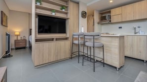 A modern kitchen with wooden cabinetry, a built-in TV, and a bar area with stools. - 7th floor modern apartment close to parque lleras (Medellín)